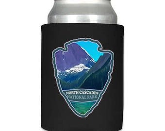 May include: Black neoprene can cooler with a blue and green image of a mountain range and a lake. The text "North Cascades National Park" is printed below the image.