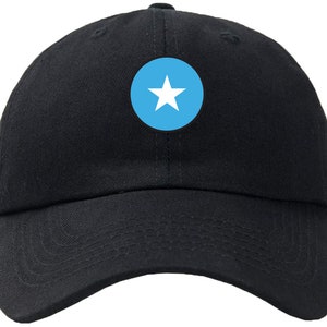 May include: A black baseball cap with a blue circle and a white star in the center. The star is the national symbol of Somalia.