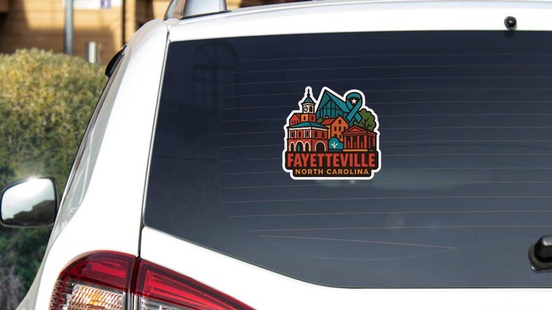 A sticker on the rear window of a white car, featuring an illustration of a city skyline with various buildings and landmarks.