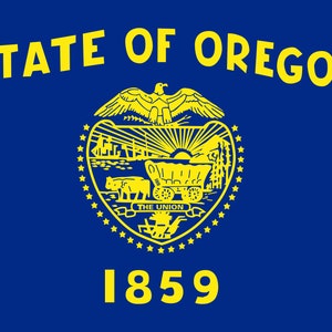 May include: The official flag of the State of Oregon, featuring a blue background with a yellow seal in the center. The seal depicts a wagon train, a mountain range, a rising sun, and a bald eagle. The text "STATE OF OREGON" appears above the seal, and "1859" appears below.
