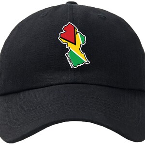 Puede incluir: Una gorra de béisbol negra con un contorno bordado de Guyana con los colores de la bandera del país: rojo, amarillo y verde. La palabra "GUYANA" está escrita en blanco debajo del contorno.