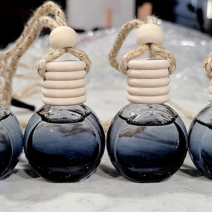 以下が含まれることがあります： 暗い青色の液体が入ったガラス製の車用芳香剤4個。それぞれに、吊り下げ用のロープと木製のボールが付いた木製のキャップが付いています。キャップは明るい色で、溝のあるデザインです。