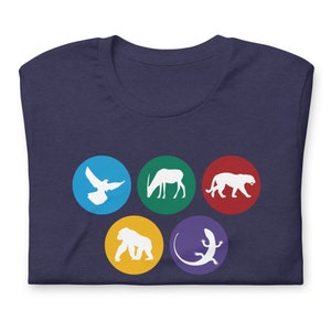 Puede incluir: Camiseta azul marino con cinco siluetas de animales en círculos de colores: una paloma, un antílope, una pantera, un gorila y un lagarto. El diseño está impreso en tela suave.