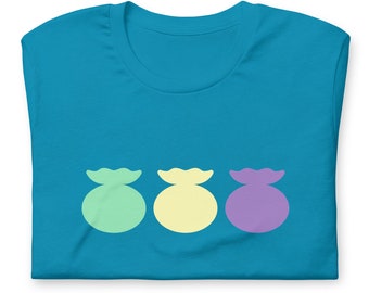 May include: A folded turquoise t-shirt featuring three stylized, rounded shapes in pastel colors: light green, yellow, and purple. The shapes are arranged horizontally across the front of the shirt. The shirt is made of a soft material.