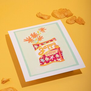 May include: A print of a bag of Zapp's Voodoo potato chips with a bouquet of orange flowers coming out of the top. The bag is red with a white border and has a pattern of small dancing figures.