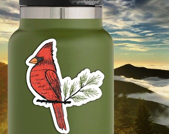 May include: A red cardinal bird perched on a pine branch. The sticker is 2 inches by 3 inches. "Life Outside Sticker Company" is printed at the top of the sticker.