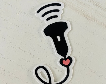 May include: Black and white sticker of an ultrasound wand with a pink heart at the end of the cord. The wand has a wavy line above it, representing sound waves.