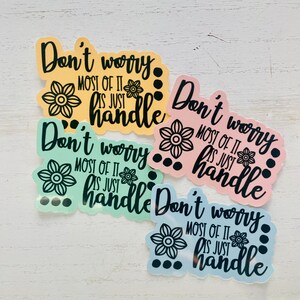 Op de afbeelding: Vier stickers in pastelkleuren met de tekst "Maak je geen zorgen. Het meeste is gewoon te hanteren." in zwarte letters. Elke sticker heeft een zwart bloemenmotief en zwarte stippen.