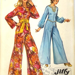 May include: Simplicity sewing pattern 9113 featuring two jumpsuits. One jumpsuit is orange with a floral pattern and a yellow belt. The other is a light blue jumpsuit with long sleeves. The pattern is for size 12, bust 34.