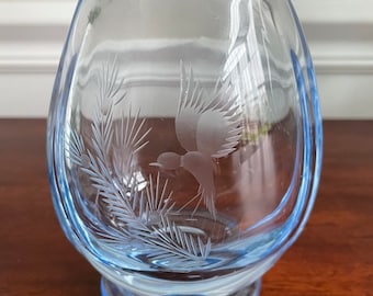 May include: A light blue glass vase with an etched design of a bird flying over a pine branch.