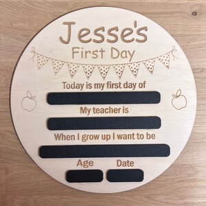 Pu&ograve; includere: Un cartello di legno con il testo "Jesse's First Day" e spazi da riempire con informazioni sul primo giorno di scuola del bambino, tra cui la data, l'et&agrave;, il nome dell'insegnante e cosa vuole fare da grande.