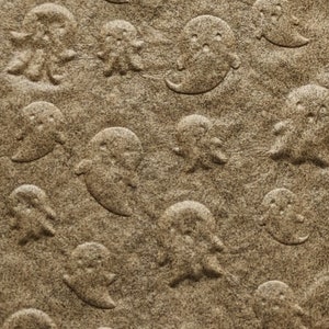 May include: A sheet of brown paper with a repeating pattern of embossed ghosts. The paper is approximately 4 inches wide and 4 inches long.