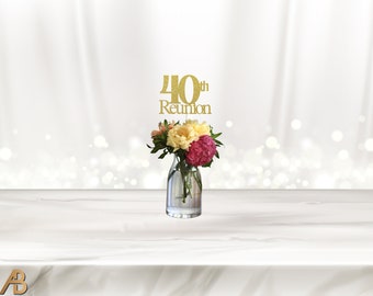 May include: Gold glitter 40th Reunion sign with a vase of pink, yellow, and white flowers.
