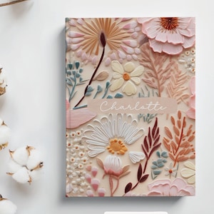 May include: A pink and cream floral notebook with the name "Charlotte" printed on the front cover. The notebook features a floral design with a variety of flowers and leaves. The text "Sweet Summer" is printed below the notebook.