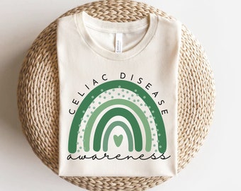 May include: A white t-shirt with a green rainbow design and the text "Celiac Disease Awareness".