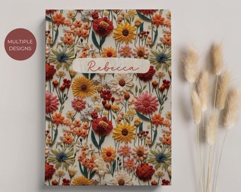 May include: A personalized notebook with a floral design featuring a variety of colorful flowers, including red, yellow, and orange. The notebook has the name "Rebecca" written on the front in a white rectangle.
