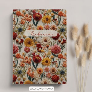 K&ouml;nnte beinhalten: Ein Notizbuch mit floralem Muster und dem Namen "Rebecca" auf dem Einband. Das Notizbuch hat einen wei&szlig;en Hintergrund mit einer Vielzahl von bunten Blumen, darunter rote, orange, gelbe und blaue.