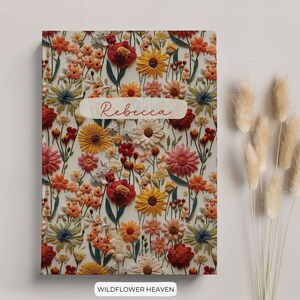 Puede incluir: Un cuaderno con estampado floral con el nombre "Rebecca" impreso en la portada. El cuaderno tiene un fondo blanco con una variedad de flores de colores, incluyendo rojo, naranja, amarillo y azul.