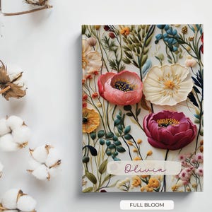 May include: A floral notebook with a white background and a variety of colourful flowers, including pink, red, and yellow. The notebook has a personalised name, "Olivia", and the text "Full Bloom" at the bottom.