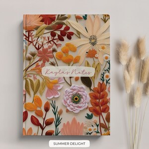 K&ouml;nnte beinhalten: Ein Notizbuchcover mit floralem Muster in Rosa, Orange und Gelb. Das Cover tr&auml;gt den Text "Kayla's Notes" in rosa Schrift.