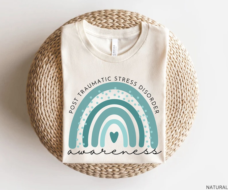 May include: A white t-shirt with a teal blue rainbow design and the text "Post Traumatic Stress Disorder Awareness".