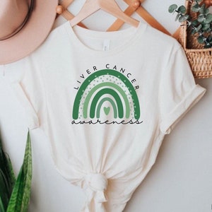 May include: A white t-shirt with a green rainbow design and the text "Liver Cancer Awareness" printed on the front.