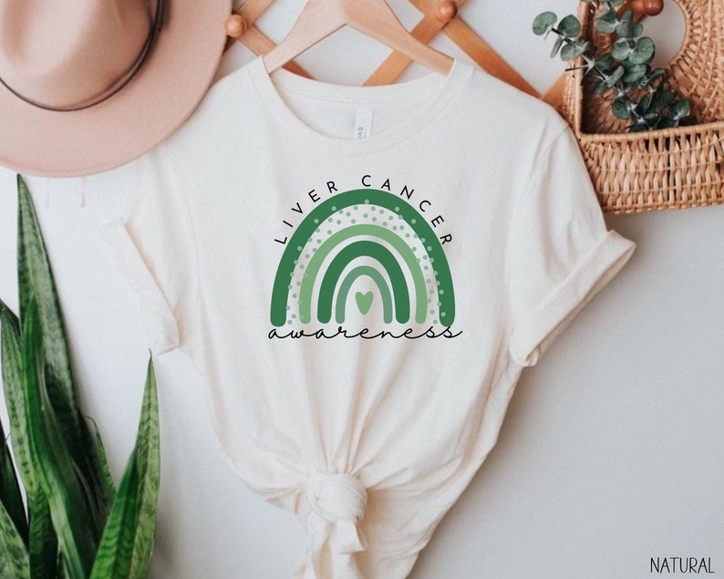 May include: A white t-shirt with a green rainbow design and the text "Liver Cancer Awareness" printed on the front.