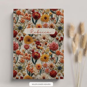 May include: A personalised notebook with a floral design featuring a variety of flowers in shades of red, orange, yellow, and white. The name "Rebecca" is printed on the front cover.