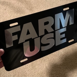 May include: Black metal license plate with silver lettering that reads "FARM USE".