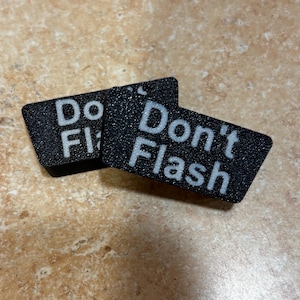 May include: Two black rectangular signs with white text. The first sign says "Do Flash" and the second sign says "Don't Flash".