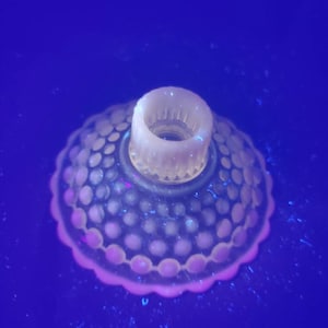 May include: A clear glass candle holder with a scalloped edge and a textured, raised dot pattern. The holder has a central opening for a candle.