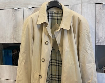 May include: A beige trench coat with a plaid lining. The coat has a button closure and two pockets on the front.
