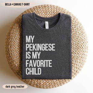 May include: Dark grey heather Bella + Canvas t-shirt with the text "My Pekingese is my favorite child" printed in white.