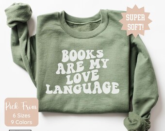 May include: A green sweatshirt with the text "BOOKS ARE MY LOVE LANGUAGE" in white, retro-style lettering. The sweatshirt is available in 6 sizes and 9 colors.