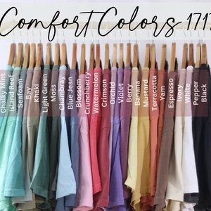 May include: A rack of 20 t-shirts in various colors, including Chalky Mint, Island Reef, Seafoam, Bay, Khaki, Light Green, Moss, Chambray, Blue Jean, Blossom, Crunchberry, Watermelon, Crimson, Orchid, Violet, Berry, Banana, Mustard, Terracotta, Yam, Espresso, Ivory, White, Pepper, and Black. The rack is labeled "Comfort Colors 1717".