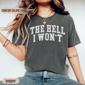 May include: A gray t-shirt with the text "THE HELL I WON'T" printed in white. The shirt is a relaxed fit and has a crew neck.