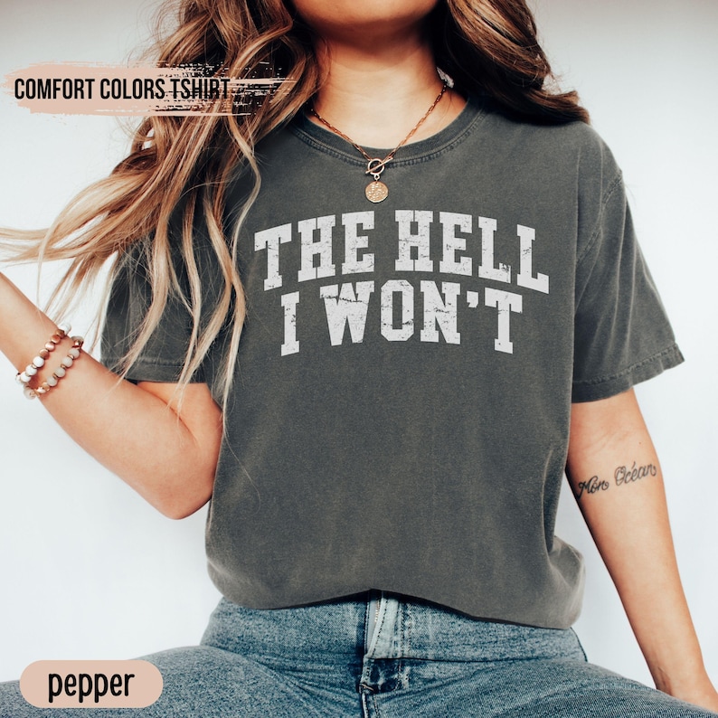 May include: A gray t-shirt with the text "THE HELL I WON'T" printed in white. The shirt is a relaxed fit and has a crew neck.