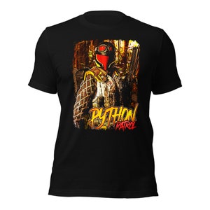 Op de afbeelding: Zwart T-shirt met een afbeelding van een persoon die een rood-zwart masker, camouflagekleding en een geweer draagt. De afbeelding is omgeven door een gele en oranje rand met de tekst "PYTHON PATROL" in gele en rode letters.