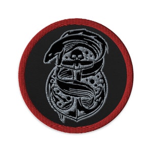 Könnte beinhalten: Runder, gestickter Aufnäher mit schwarzem Hintergrund und rotem Rand. Der Aufnäher zeigt ein detailliertes, stilisiertes Design in Grautönen, darunter ein Totenkopf, eine Schlange und verzierte Schnörkel.