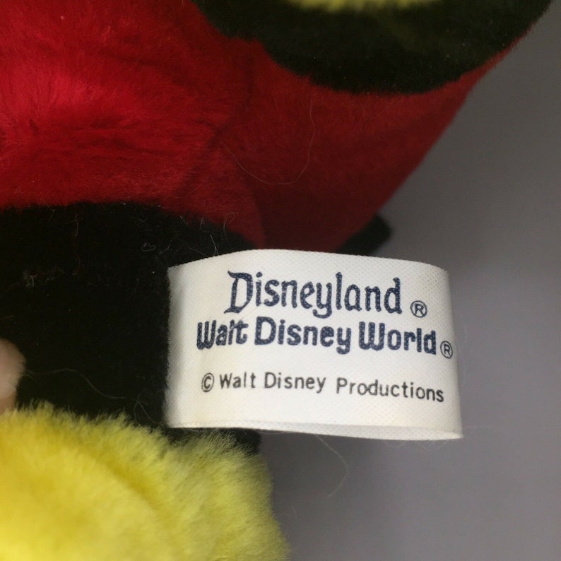 May include: White tag with blue text that reads "Disneyland&reg; Walt Disney World&reg; &copy; Walt Disney Productions".