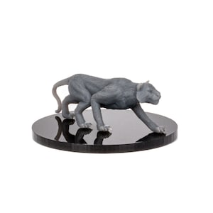 May include: A gray painted miniature figurine of a panther or cougar, posed in a stalking position, on a black circular base.