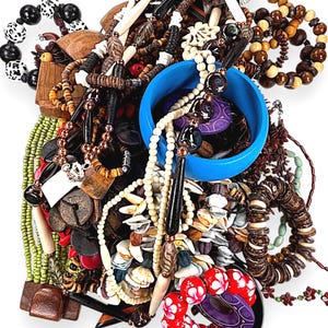 May include: A collection of various necklaces and bracelets in a variety of colors and materials. The jewelry includes wooden beads, shells, and other natural elements. A blue bangle and red and white beaded bracelet are also visible.
