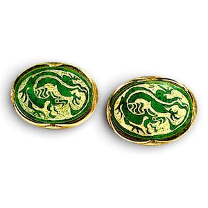 May include: A pair of oval-shaped cufflinks featuring a gold-toned metal frame and a green inlay. Each cufflink displays a detailed, etched gold-colored dragon motif centered within the green surface, creating a distinct contrast between the metallic gold and the deep green background.
