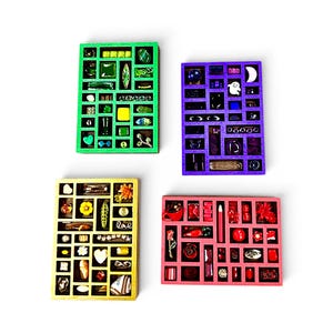 Puede incluir: Cuatro bandejas de madera coloridas, cada una dividida en pequeños compartimentos, llenas de varios objetos decorativos. Las bandejas son verdes, moradas, amarillas y rosas. La bandeja verde contiene objetos verdes, la bandeja morada tiene objetos morados, la bandeja amarilla tiene objetos amarillos y la bandeja rosa tiene objetos rosas.
