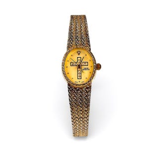 Puede incluir: Un reloj de pulsera dorado con un diseño de cruz en la esfera. El reloj presenta una correa texturizada y una esfera redonda con el texto "SARAH COVENTRY". Un pequeño diamante se encuentra en la posición de las 12.