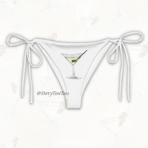 May include: White string bikini bottom with a martini glass graphic and the text "@DirtyTiniTees" printed on the front.