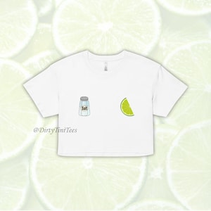 May include: White cropped t-shirt with a salt shaker and a lime wedge graphic. The text "Salt" is printed on the salt shaker. The text "@DirtyTimiTees" is printed below the graphic.