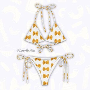 May include: White bikini with a bowtie pasta print. The top is a triangle style with adjustable straps. The bottom is a cheeky style with ties on the sides.