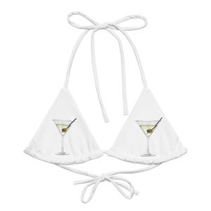 May include: A white triangle bikini top featuring a graphic print of a martini glass with a green olive on each cup. The garment includes thin white fabric ties at the neck and back, designed with a classic halter silhouette and adjustable sliding cups.