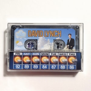 May include: A clear plastic cassette tape with a blue and white weather forecast design. The tape features the text "THE WEATHER CHANNEL" and "DAVID LYNCH". The forecast shows a sunny sky with temperatures ranging from 84 to 92 degrees Fahrenheit.